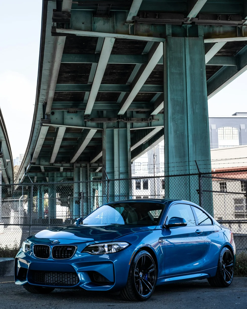 Niebieskie sportowe BMW coupé pod betonowym wiaduktem, fotografia Michaela Yuana